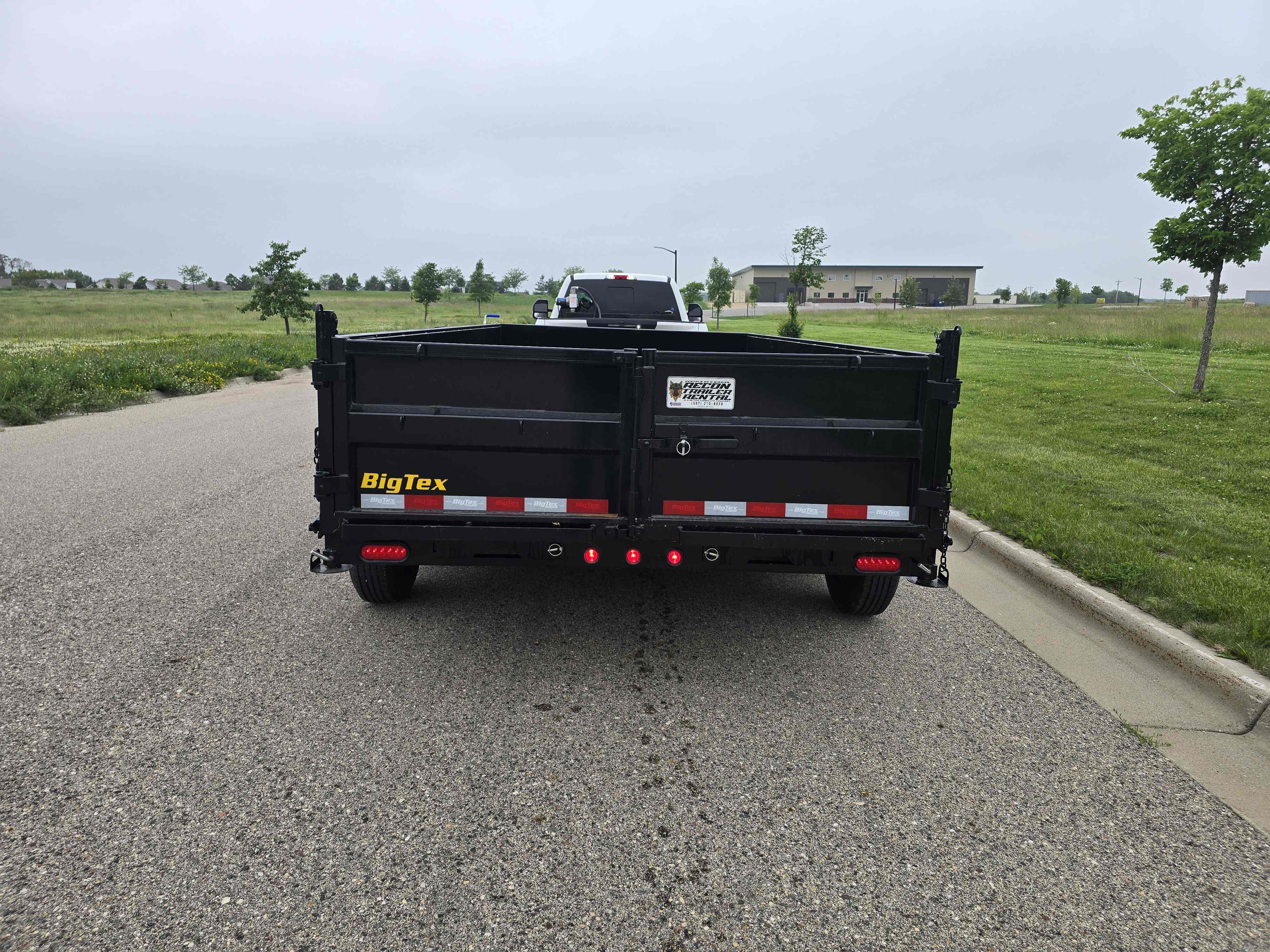 BigTex dump trailer rear view hitched to a truck on a paved road