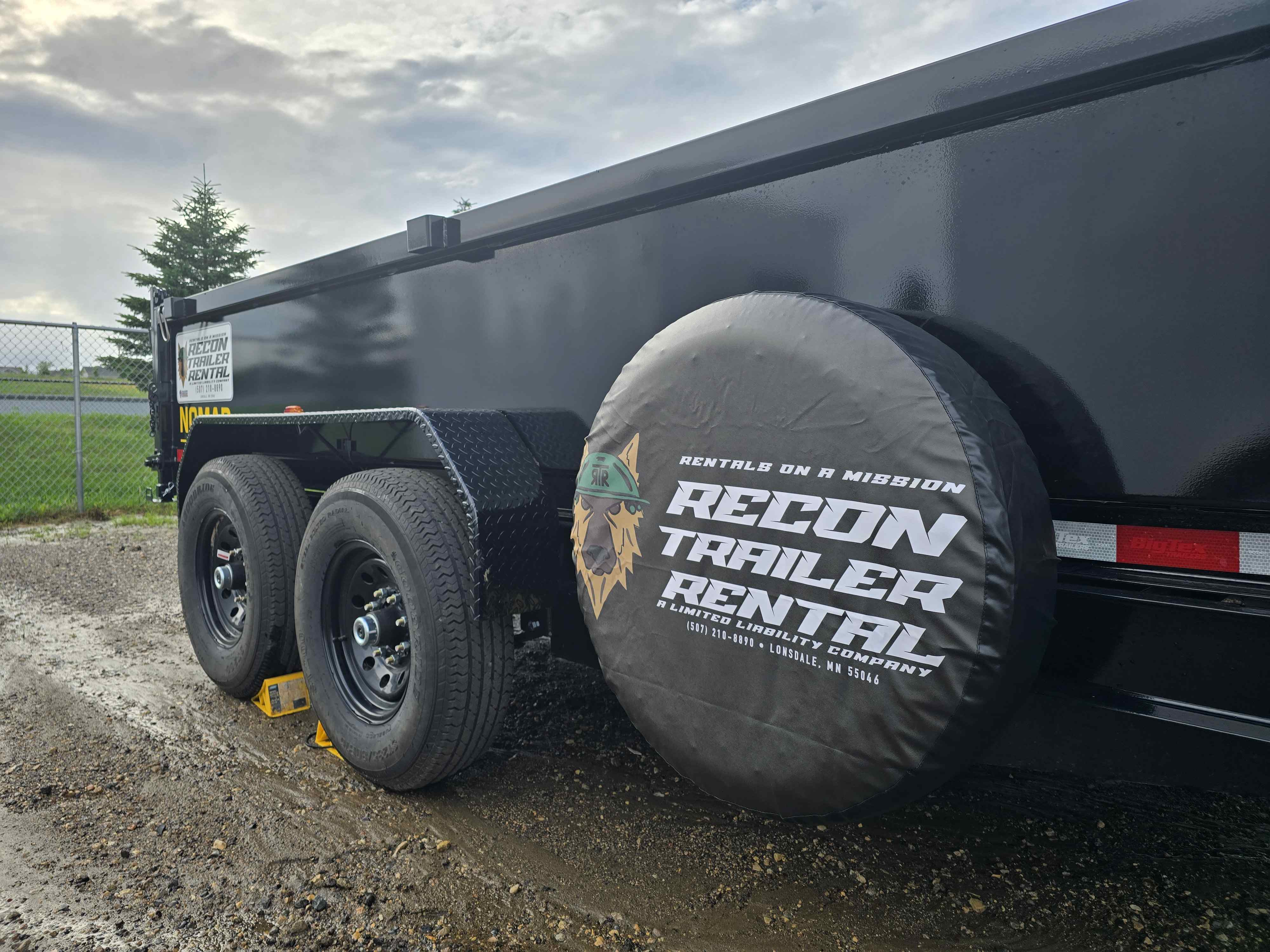Close-up of BigTex dump trailer wheel with Recon Trailer Rental spare tire cover