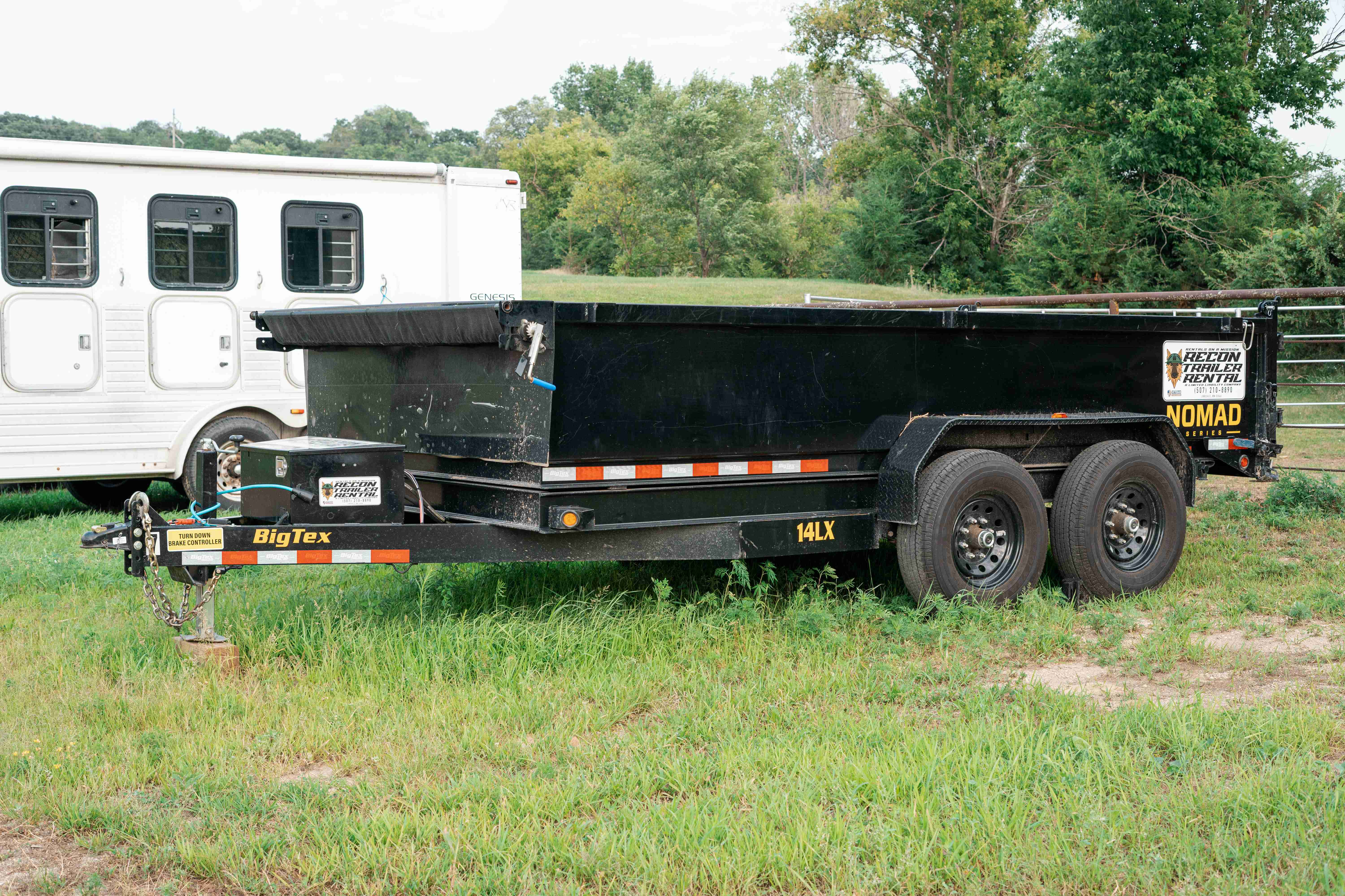 BigTex 14ft dump trailer side profile parked in grass field next to horse trailer