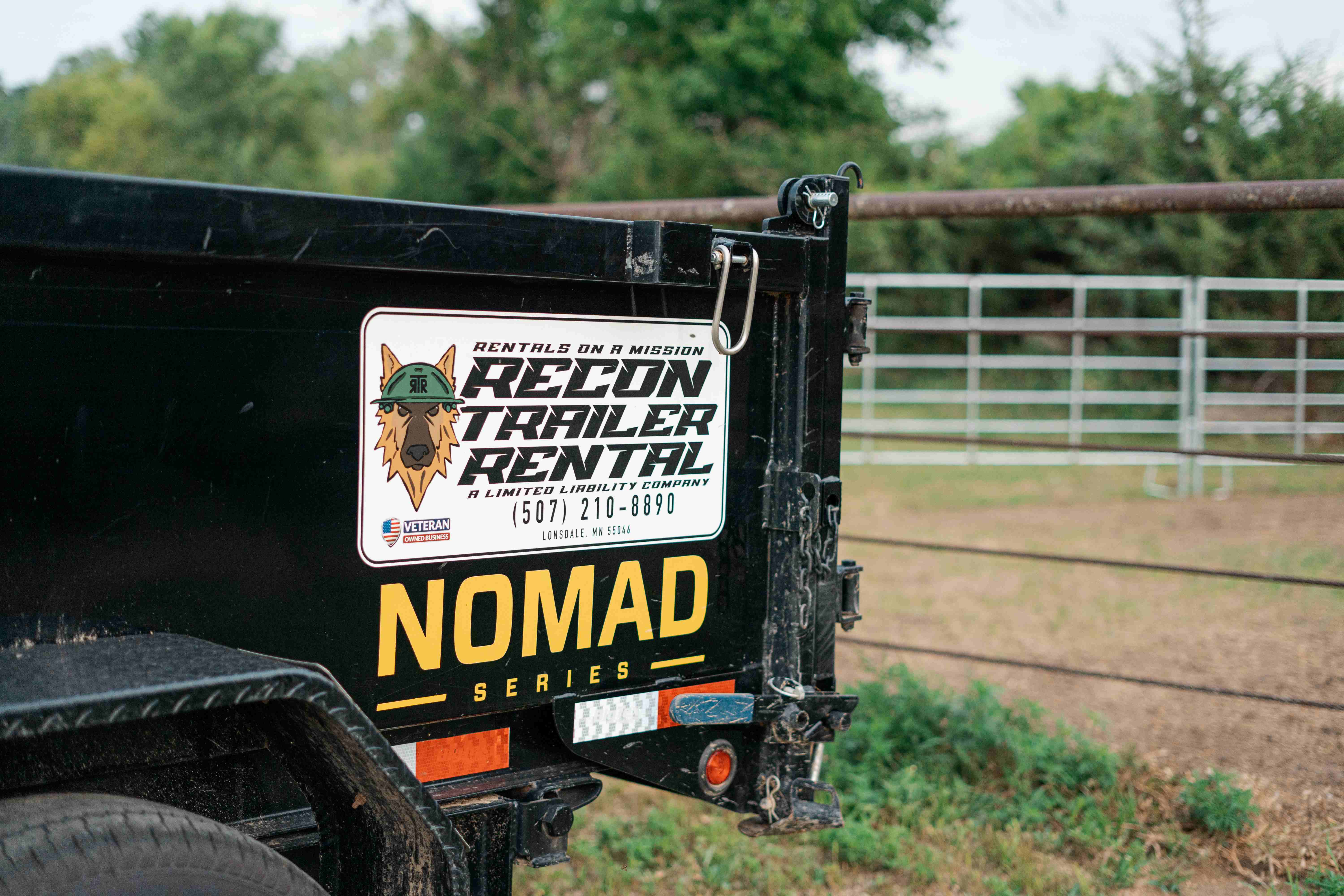Close-up of BigTex dump trailer NOMAD tailgate latch and Recon Trailer Rental sticker