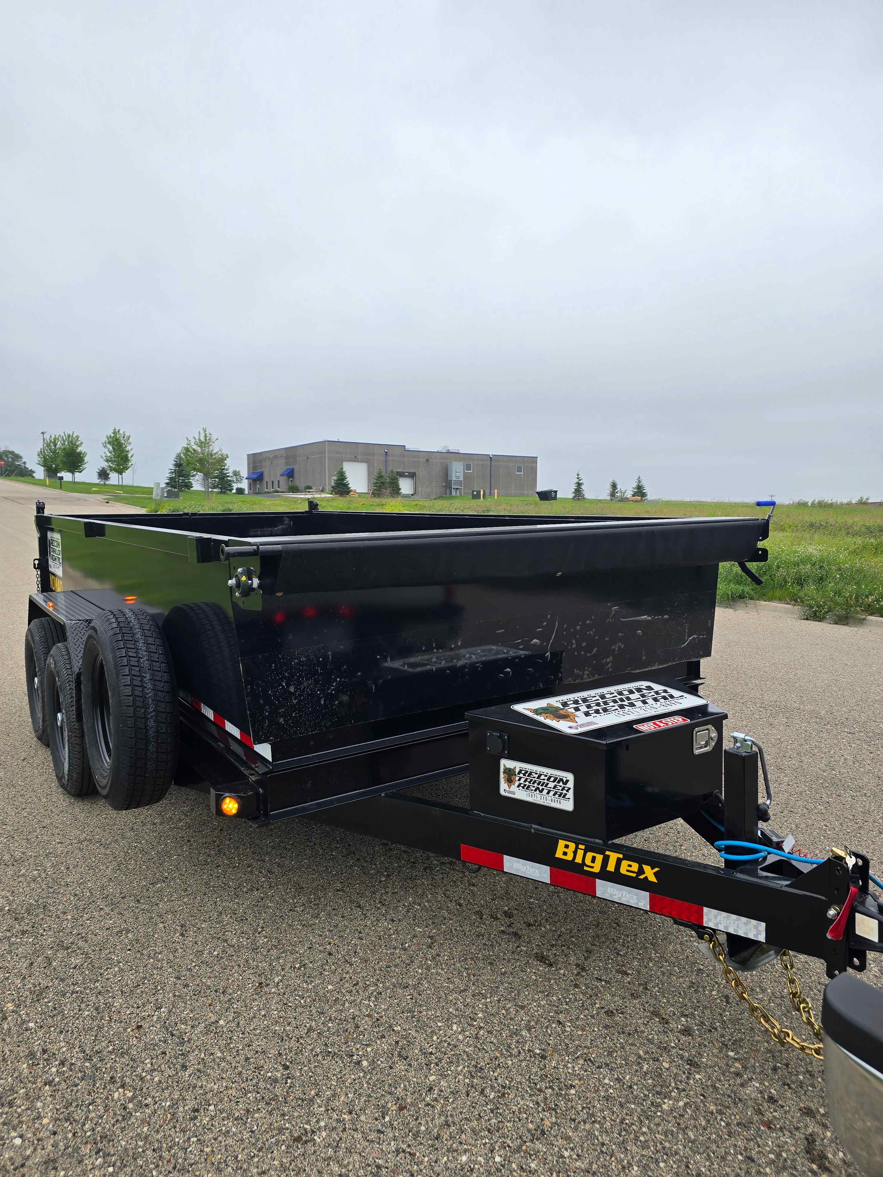 BigTex 14K NOMAD dump trailer rear angle view on pavement near commercial building