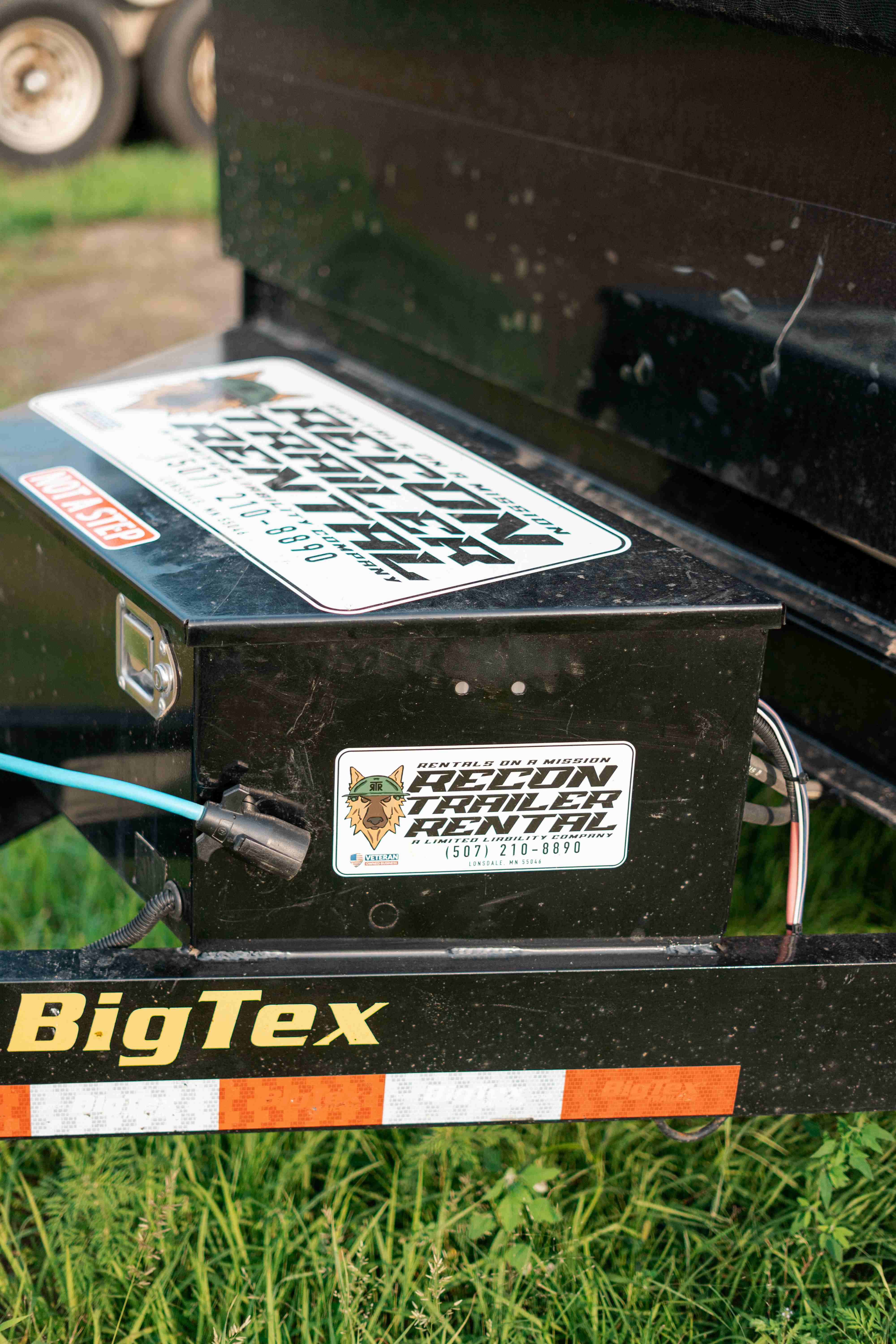 Top-down close-up of BigTex dump trailer tongue toolbox with Recon Trailer Rental branding