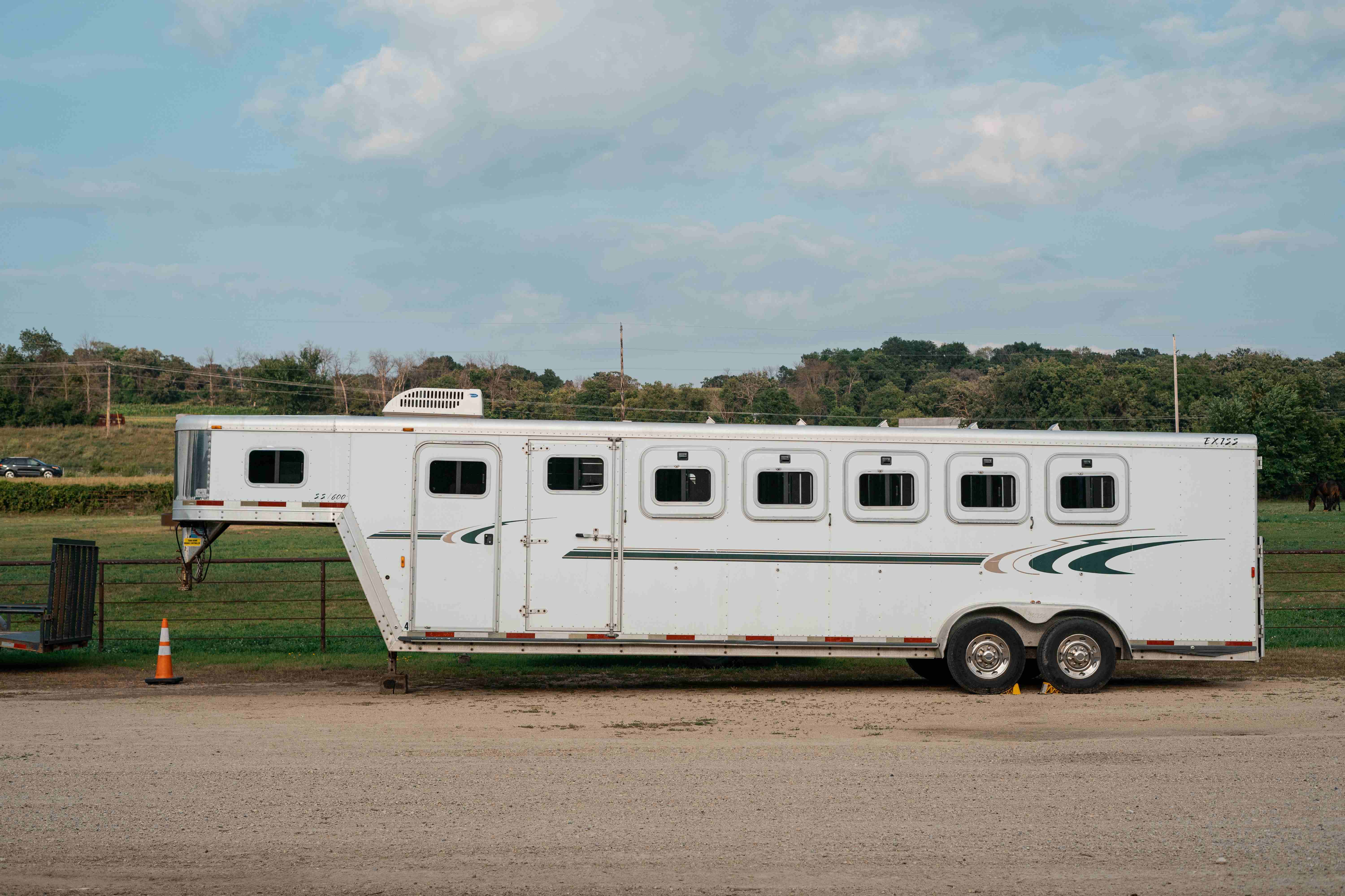 Exiss SS600 horse trailer side profile parked in a dirt lot next to a metal gate