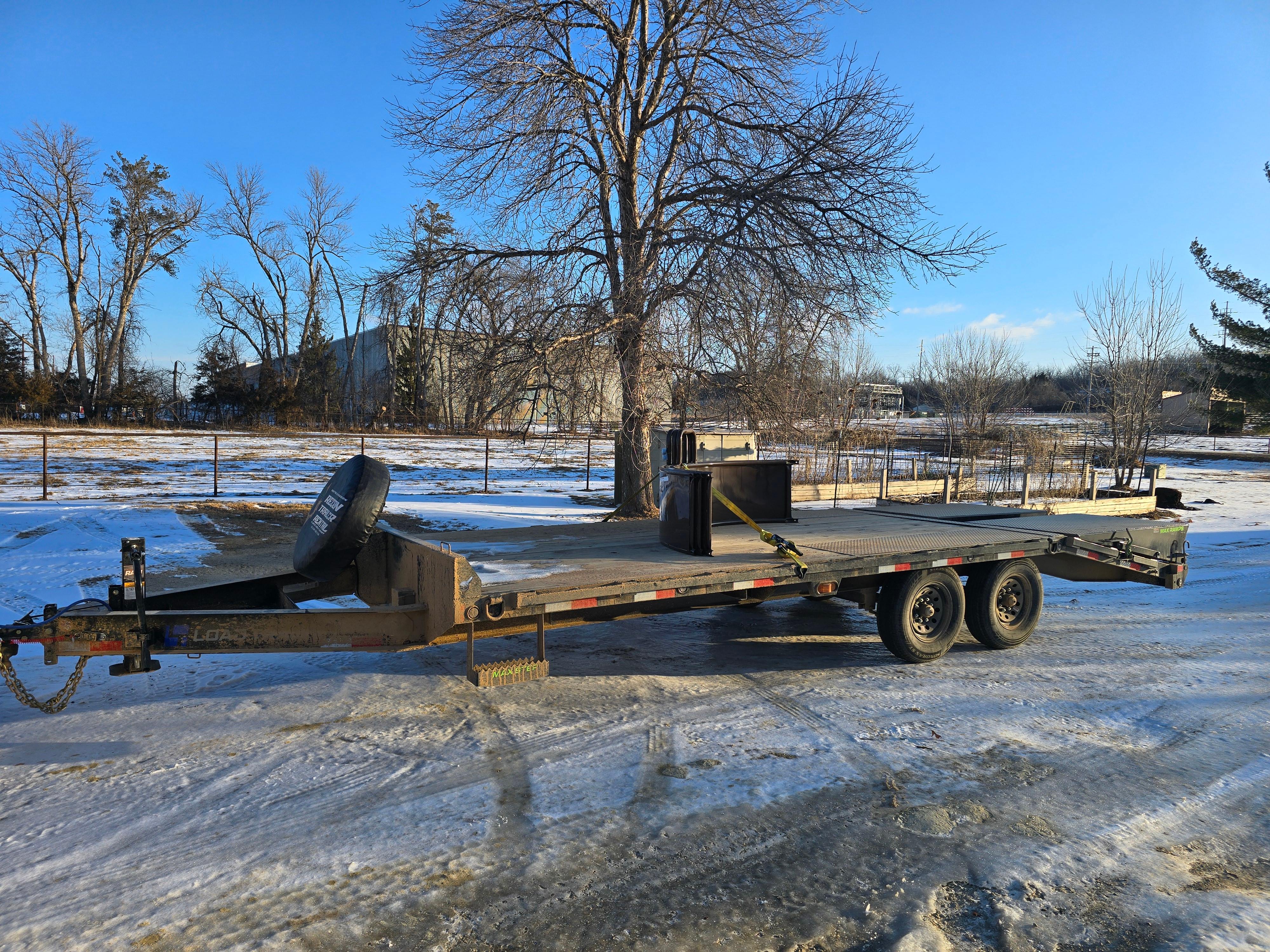 Load Trail deckover trailer front angle in winter showing spare tire mount, drop leg jack, and full deck length