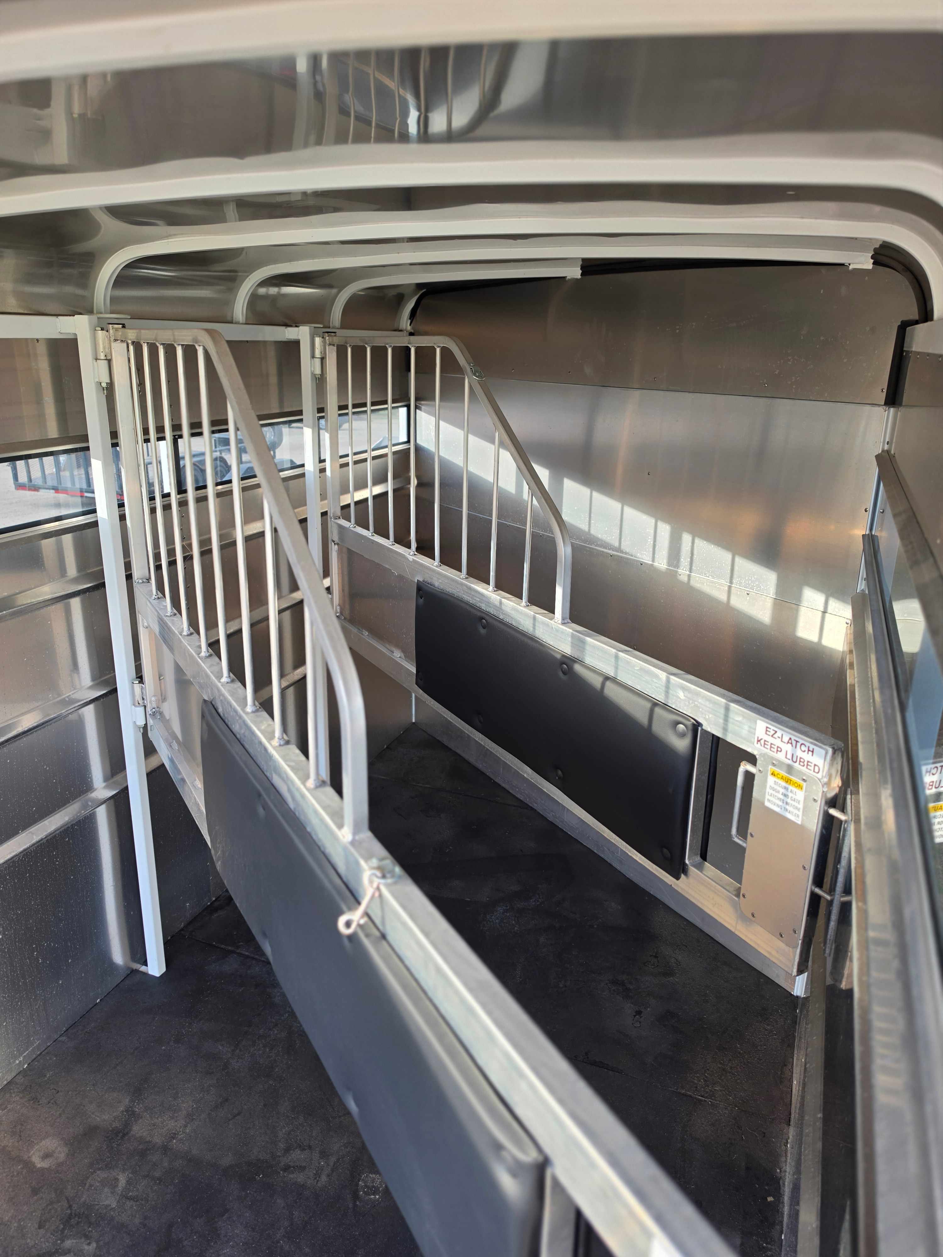 Interior of the 3 horse stock combo showing aluminum divider gates, padded partitions, and rubber flooring